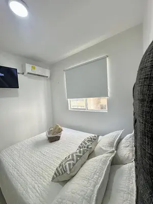 a white bedroom with a bed with a window at Apartamento vacacional cerca del mar in Cartagena de Indias