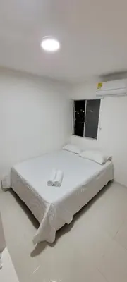 a white bedroom with a bed with two towels on it at Hermoso apartamento cerca a las playas de Marbella en Cartagena in Cartagena de Indias