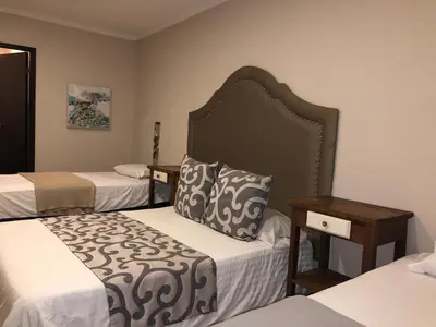a hotel room with two beds and two tables at Hotel Galeria la Trinidad in Cartagena de Indias