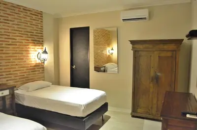 a bedroom with two beds and a mirror at Hotel Galeria la Trinidad in Cartagena de Indias