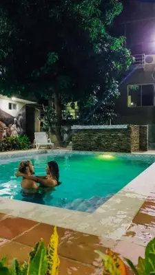 two people hugging in a swimming pool at night at Hostal Los Arhuacos in Santa Marta