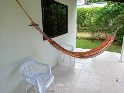 a hammock in a room with two chairs and a window at Mágica Cabaña familiar cerca al mar in Coveñas