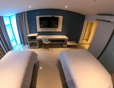 a room with two beds and a desk and a table at HOTEL MANZUR in Barranquilla