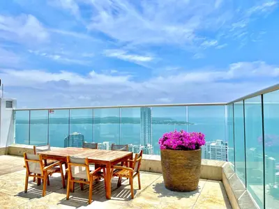 a table and chairs on a balcony with a view of the ocean at by Calamari Homes - Palmetto Beach 2504 Bocagrande in Cartagena de Indias