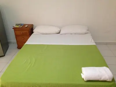 a bed with a green blanket on it with a night stand at Cecil Aparta Estudios in Barranquilla