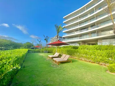 a lawn with two lounge chairs and an umbrella in front of a building at Fantastic Apartment/Beach Front Luxury in Cartagena de Indias