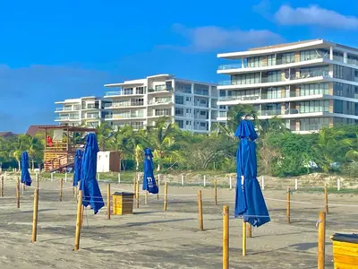 a bunch of blue umbrellas on a beach with a building at Fantastic Apartment/Beach Front Luxury in Cartagena de Indias