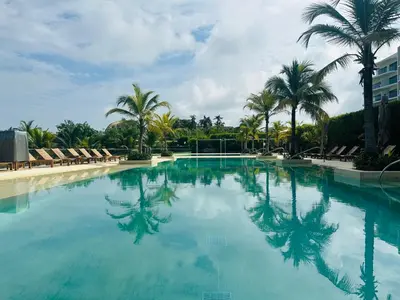 a large swimming pool with palm trees and chairs at ¡Wonderful Beach Loft! in Cartagena de Indias