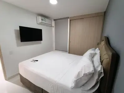 a small bedroom with a white bed and a flat screen tv at Moderno apartamento al norte de Barranquilla in Barranquilla