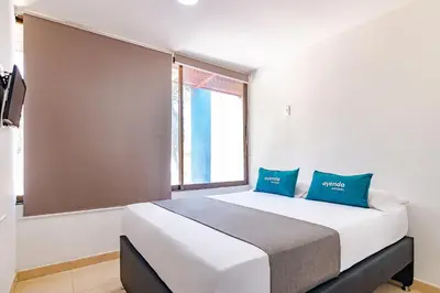 a bedroom with a large white bed with blue pillows at Ayenda Casa Amarilla in Santa Marta