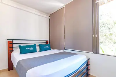 a bedroom with a bed with blue pillows and a window at Ayenda Casa Amarilla in Santa Marta