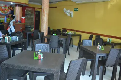 a dining room with tables and chairs and a woman in the background at Hotel Granada Inn in Barranquilla