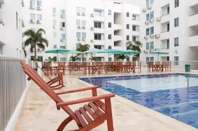 a pool with chairs and umbrellas next to a hotel at Apartamento en Caribe campestre Coveñas in Coveñitas