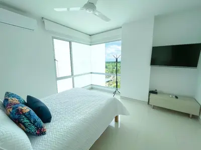 a white bedroom with a bed and a flat screen tv at Magico Apartamento Frente al Mar 4 Habitaciones O62 in Coveñas