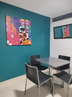 a dining room with a table and chairs and a painting at Hotel Boston Superior in Barranquilla