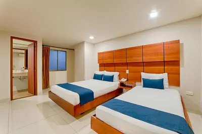 a hotel room with two beds and a bathroom at Hotel Caribe 79 in Barranquilla