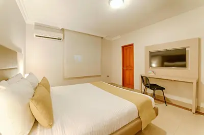 a bedroom with a bed and a desk and a television at Hotel Caribe 79 in Barranquilla