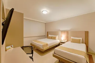 a hotel room with two beds and a desk at Hotel Caribe 79 in Barranquilla