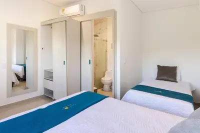 a bedroom with two beds and a bathroom with a mirror at Amazing Beach House 13BR w/Pool & Staff in Cartagena de Indias
