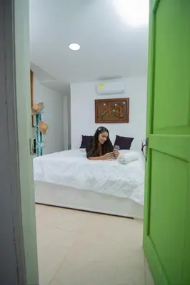 a woman laying on a bed looking at her cell phone at Casa Playa James in La Boquilla