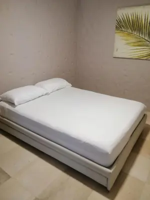 a bed with white sheets and pillows in a room at Capitel Hostel in Cartagena de Indias