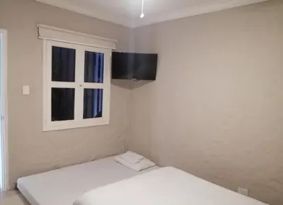 a white room with two beds and a window at Capitel Hostel in Cartagena de Indias