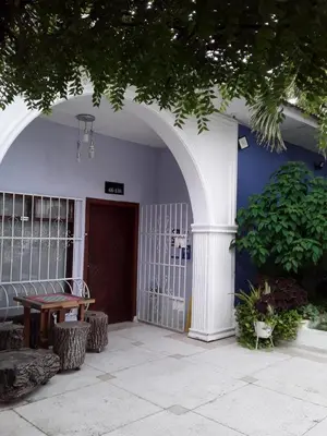 a building with an arch with a table and a door at Hostel Mamy Dorme in Barranquilla
