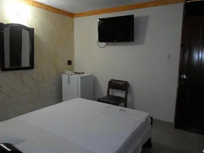 a bedroom with a bed and a chair and a tv on the wall at Hotel Colonial Inn in Barranquilla