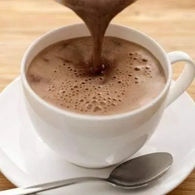 a cup of coffee on a white plate with a spoon at Hotel Colonial Inn in Barranquilla