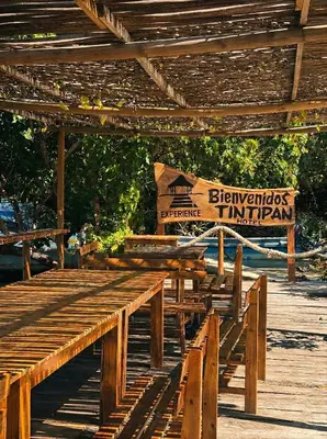 a group of wooden benches sitting under a wooden structure at Tintipan Hotel in Tintipan Island