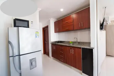 a kitchen with a white refrigerator and wooden cabinets at AL-1C APARTAMENTO DE 1 ALCOBA CERCA AL MAR AIRE ACONDICIONADO WIFi Y PISCINA in Cartagena de Indias