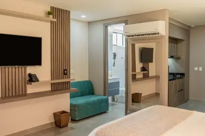 a hotel room with a television and a blue couch at Amari Living Suites in Barranquilla