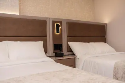 two beds in a hotel room with white sheets at Amari Living Suites in Barranquilla