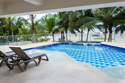 a swimming pool with two lounge chairs next to a resort at 2 Dormitorios Morros. Vista Ciénaga y salida playa in Cartagena de Indias