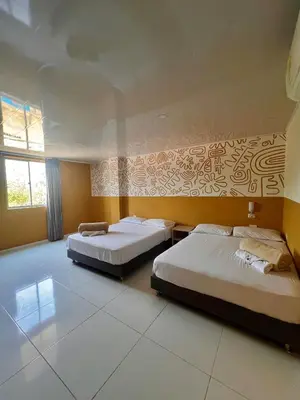 two beds in a room with yellow walls at Hotel Paranawa in Baranoa