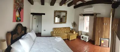 a bedroom with a bed and a couch and a mirror at EMMA HOTEL SAN DIEGO in Cartagena de Indias