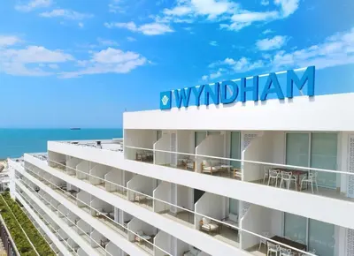 a white building with the ocean in the background at Wyndham Residences Santa Marta Aluna Beach Club in Santa Marta