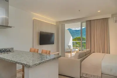 a bedroom with a bed and a living room with a view at Wyndham Residences Santa Marta Aluna Beach Club in Santa Marta