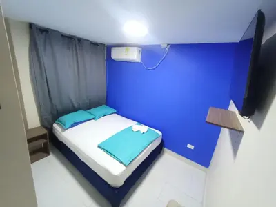 a small blue room with a bed and a television at CASA HOTEL YEMI in Barranquilla