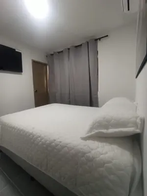 a bedroom with a white bed and a television at CASA HOTEL YEMI in Barranquilla