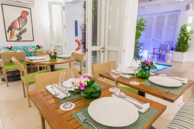 a dining room with wooden tables and white plates and chairs at Casa La Cartujita in Cartagena de Indias