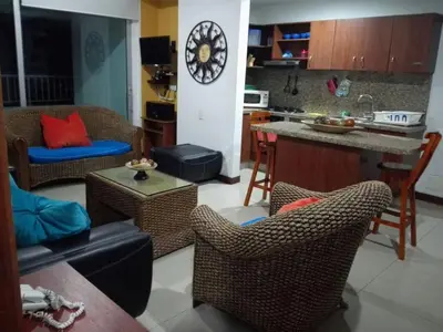 a living room with chairs and a kitchen with a clock at Apto en Cartagena de Indias in Cartagena de Indias