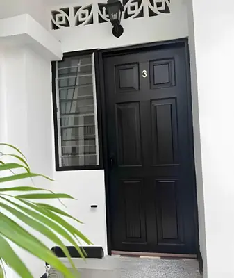 a black door on a white house with a plant at Céntrico y confortable apto Casa Doña Yola 3 in Cartagena de Indias