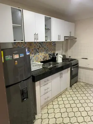 a kitchen with white cabinets and a black refrigerator at Apartahotel Edificio Baquero x5 Apto 201 in Barranquilla