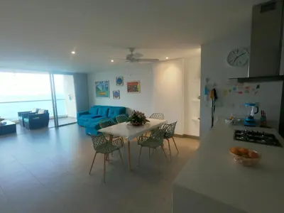a kitchen and living room with a table and a blue couch at exclusivo apartamento con doble vista al mar en santa marta # in Santa Marta