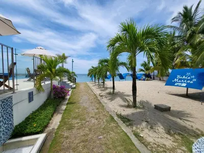 a pathway to the beach with palm trees and a sign at Yellow beach & rest in Coveñas