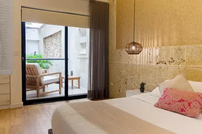 a bedroom with a bed and a balcony with a chair at Cartagena Suites de Manga in Cartagena de Indias