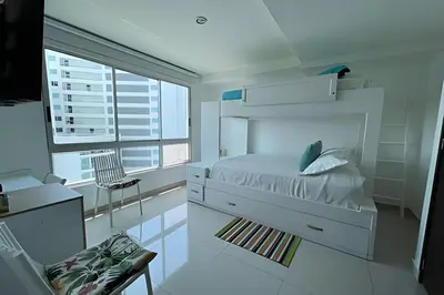 a white bedroom with a bed and a chair at 2 dormitorios Morros. Vista Panorámica y salida Playa in Cartagena de Indias