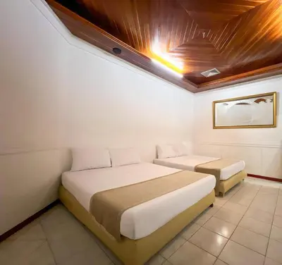two beds in a room with a ceiling at Hotel Barranquilla Prado in Barranquilla