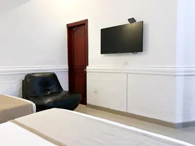 a bedroom with a black leather chair and a flat screen tv at Hotel Barranquilla Prado in Barranquilla